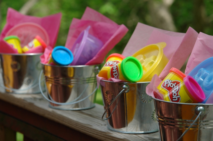 Alternative goody bags: metal reusable pails with brightly colored containers of playdough and kinetic sand.