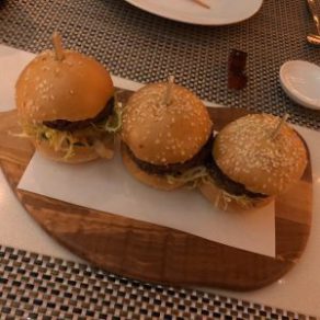 Three Impossible burger sliders on a wooden serving tray.
