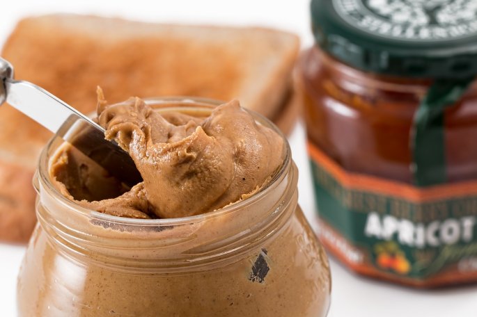 Open jar of peanut butter with butter knife in jar